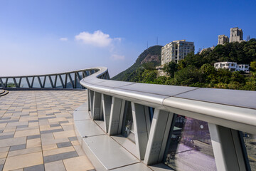 A modern curved Rooftop of Peak Galleria with a metal railing and glass panels overlooking Victoria Peak in Hong Kong.