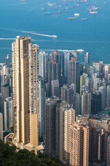 Fototapeta premium A panoramic view of Hong Kong dense cityscape, showcasing towering skyscrapers and a lush green hillside. The blue sky with a single fluffy cloud provides a picturesque backdrop.