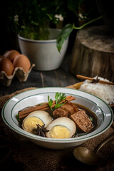 Brown boiled eggs with condiments in a bowl (braised eggs), rich broth, fragrant with herbs, a home-cooked Asian dish.
