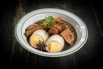 Brown boiled eggs with condiments in a bowl (braised eggs), rich broth, fragrant with herbs, a home-cooked Asian dish.