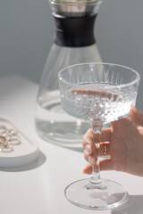 An elegant girl holds a glass of clean water in her hands, a hand with an elegant light manicure, a luxurious lifestyle, a mockup for lifestyle content, expensive manicure, summer and a healthy habit
