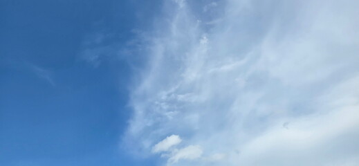 Fototapeta premium The blue sky is left and the white clouds on the right of the picture. Thin clouds are floating. The clear blue sky has some clouds. The empty blue background is elegant. Sky is clear in summer. 