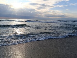 Tranquil ocean waves lapping on sandy beach under cloudy sky  