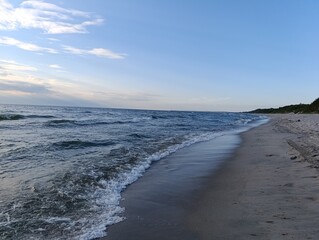 Tranquil beach with gentle waves under a blue sky at sunset  