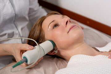Non-invasive facial lifting: woman undergoing microcurrent therapy for firmer skin