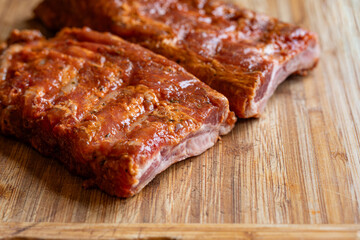 Raw, seasoned and marinate pork ribs or spare ribs on a wooden kitchen board. Close up shot, no people