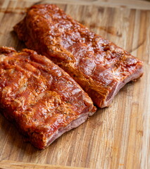 Raw, seasoned and marinate pork ribs or spare ribs on a wooden kitchen board. Close up shot, no people