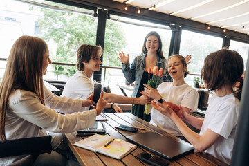 Giving the flowers, celebrating. Group of young friends are in the cafe restaurant