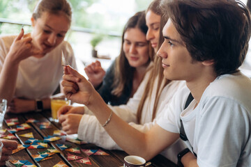 Wellness, playing card game. Group of young friends are in the cafe restaurant