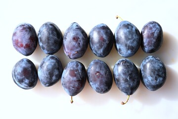 Fresh organic plums arranged neatly on a white background. A symbol of natural beauty and health, rich in vitamins and antioxidants. Perfect for healthy lifestyle themes.