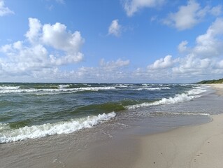 Scenic beach with waves and clouds under a bright blue sky  