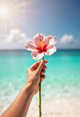 Female hand holding beautiful exotic flower against azure sea and sky