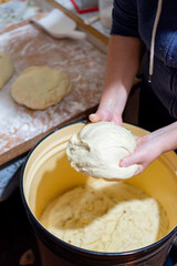 Female hands kneading fresh bread dough in large bowl, close-up