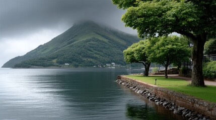 Lush trees frame the tranquil waters, while a misty mountain peak rises dramatically in the background, creating a serene atmosphere