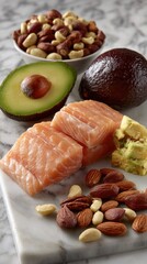Various healthy food items like salmon and avocados are elegantly arranged in white bowls on a light grey marble surface