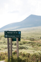 Hiking trail sign at Rondane National Park with the peak Formokampen in the background