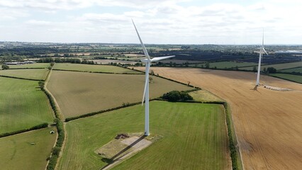 Aerial drone shot of wind turbines renewable power plant windmills generating electrical energy in England UK sunny day rural landscape.