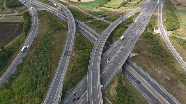 Aerial drone shot of busy motorway junction intersection with numerous bridges and lanes and vehicles near Rugby England UK M1 highway 