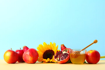 Ripe apples, pomegranates, sunflower, and honey on pastel background. Celebrating Rosh Hashanah...