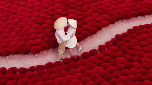 Trip of Lover couple in Viet, two tourists are walking on traditional aroma red incense production Vietnam Aerial view.