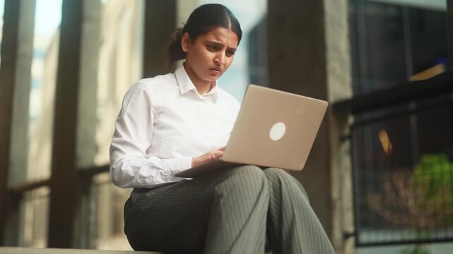 Nervous young indian businesswoman closed laptop computer with unsuccessful business project Stressed female expressing negative emotion while has professional problem mistake error outdoors