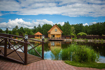 Fototapeta premium A wooden bridge over a pond with a house in the background