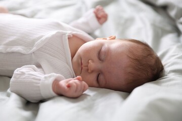 Cute newborn baby sleeping on bed, closeup