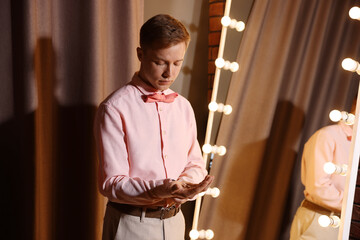 Man with cufflinks getting ready near mirror indoors