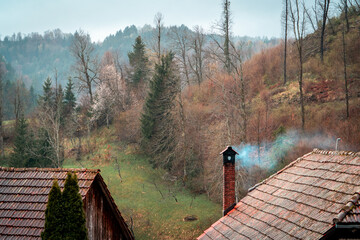 Hermosa postal de una casa de montaña con su hoguera encendida y largando humo por la chimenea. Concepto de vida tranquila de en el bosque. © Javier