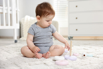 Fototapeta premium Cute little baby playing with toy pyramid in room