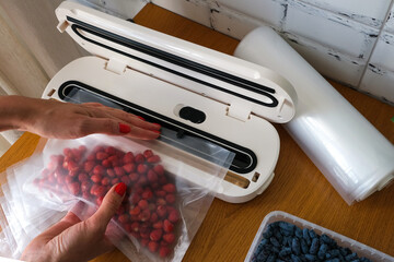 Vacuum sealer of strawberries, honeysuckle in bag, packaging for long-term storage . Vacuum packing machine