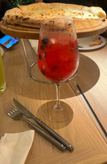 A refreshing cranberry-infused spritz tantalizes under golden sunlight, beside hearty focaccia, perfect for Hygge gatherings and Midsummer revelry