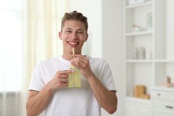 Happy man with mason jar of lemonade at home. Refreshing drink