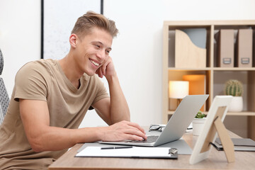 Copywriter using laptop at wooden table indoors