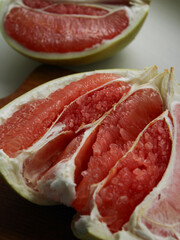 Close-up pomelo or grapefruit segments showing thick white pith and red flesh