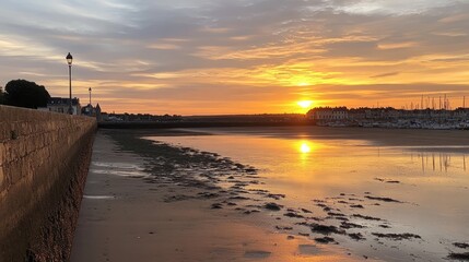Fototapeta premium Beautiful sunset over the beach at low tide in Chtelaillon-Plage near La Rochelle, golden reflections dancing on wet sand in southwest France