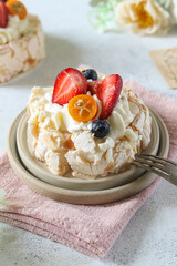 Delicious meringue dessert topped with fresh fruits served on a wooden plate during a sunny afternoon