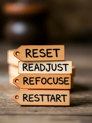 Motivational and inspirational words. RESET, READJUST, REFOCUS, RESTART written on wooden tags. With blurred styled background.