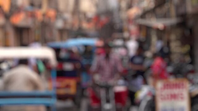 Bokeh view of road traffic at the small streets of Old Delhi, India. View of crowds of people and rickshaws around Chandni Chowk, one of the oldest and busiest markets. Blurred background footage.