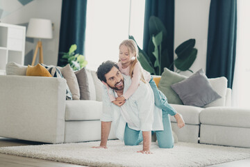 Happy father enjoying playful bonding moment with daughter at home in a cozy living room setting...
