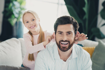 Happy father playing around with his daughter enjoying a fun and bonding moment together indoors at their comfortable home