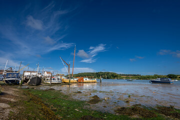 Boats on a sunny day at the quay in the historic town of Woodbridge in Suffolk, UK. View at low tide on the River Deben.