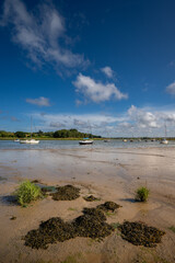 River Deben at low tide with small boats on a sunny day. View near the historic town of Woodbridge in Suffolk, UK.