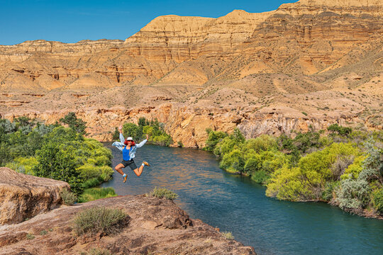 Happy hiker jumping celebrating Kazakhstan Charyn Canyon nature landscape, enjoying freedom and adventure during summer sunny day