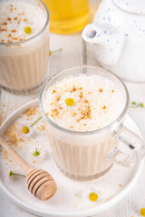 Calming natural chamomile flowers tea latte, organic late night cozy warm beverage with milk and floral chamomile tea, with honey and ginger spices