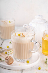 Calming natural chamomile flowers tea latte, organic late night cozy warm beverage with milk and floral chamomile tea, with honey and ginger spices