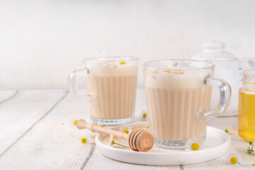 Calming natural chamomile flowers tea latte, organic late night cozy warm beverage with milk and floral chamomile tea, with honey and ginger spices