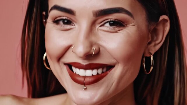Close-up portrait of a smiling young woman with facial piercings&mdash;gold nose ring and lip (labret) piercing, bold brows and red lipstick, perfect teeth (4K, 16:9).