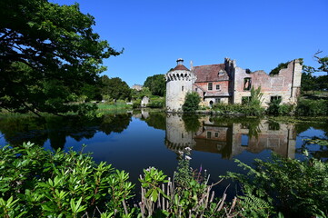 Obraz premium Ruins of a Medieval Moated Manor house by a lake in summertime.