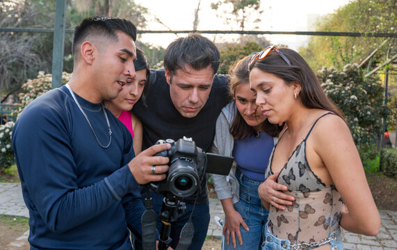 Photographer and crew reviewing photos on a camera outdoors